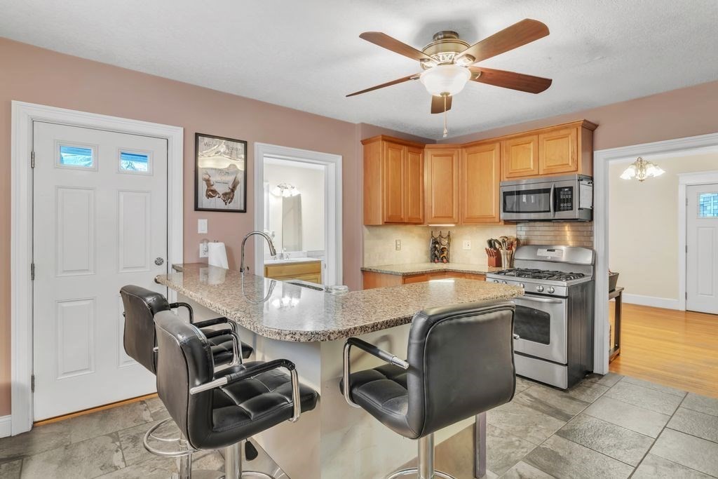 754 White Street Springfield, MA 01108 - Photo 9 of 41 a kitchen with stainless steel appliances granite countertop a stove top oven a sink a dining table and chairs with wooden floor