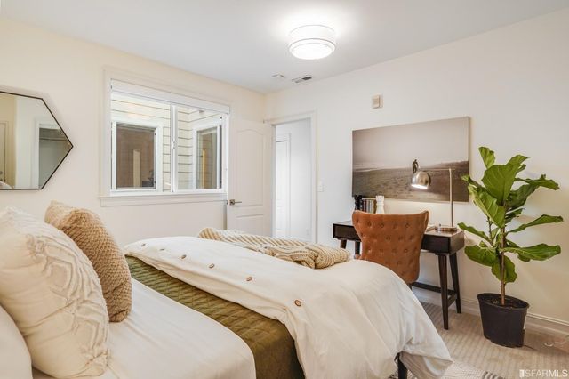 a bedroom with a bed table flowerpot and window