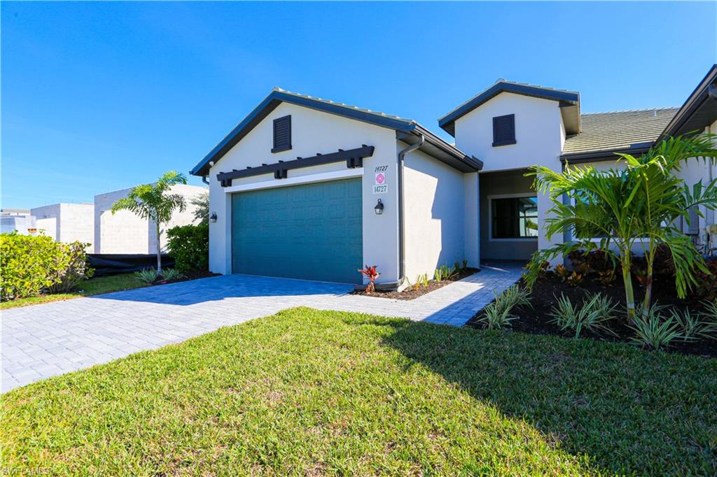 14727 Kingfisher Loop Naples, FL 34120 - Photo 2 of 50 a front view of a house with a yard and garage