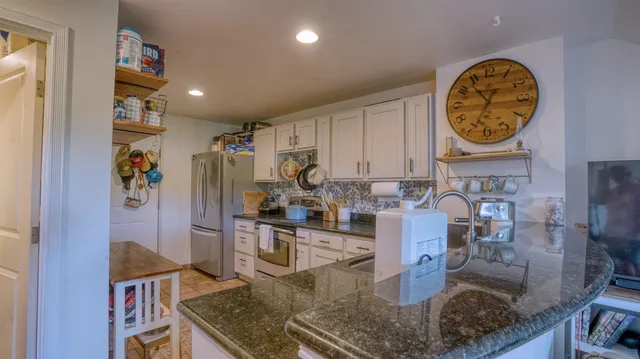 a kitchen with stainless steel appliances granite countertop a sink a stove and a wooden cabinets