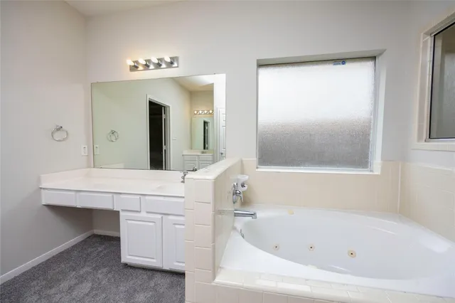 a bathroom with a bathtub a mirror a sink and vanity