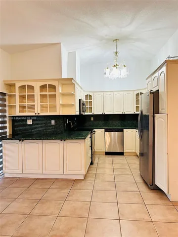 a view of a kitchen with a refrigerator and a stove top oven