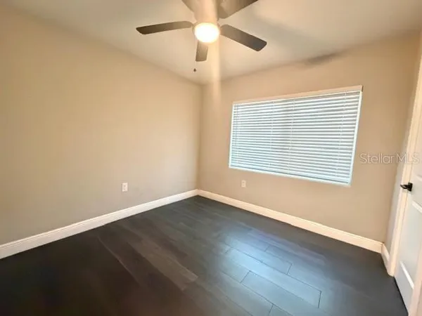 an empty room with wooden floor fan and windows
