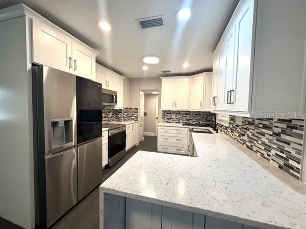 a large kitchen with a large window and stainless steel appliances
