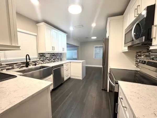 a kitchen with stainless steel appliances kitchen island granite countertop a stove a sink and a microwave