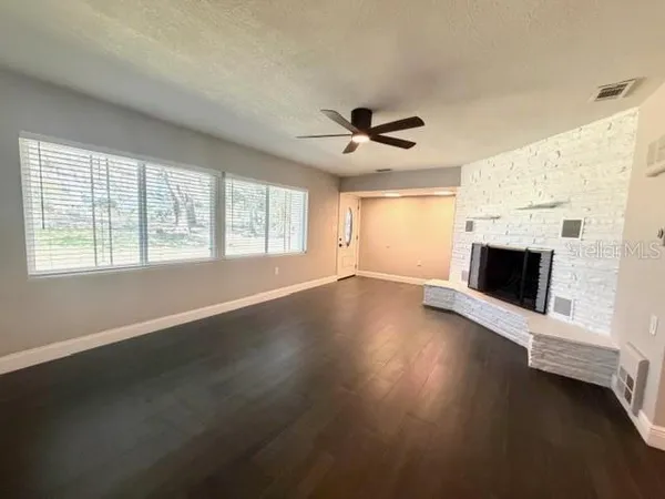 a view of empty room with fireplace and wooden floor