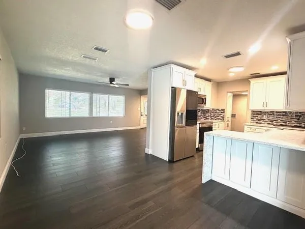 a view of a kitchen with a refrigerator wooden floor and a window