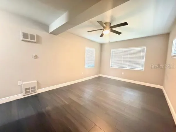 a view of an empty room with window and wooden floor