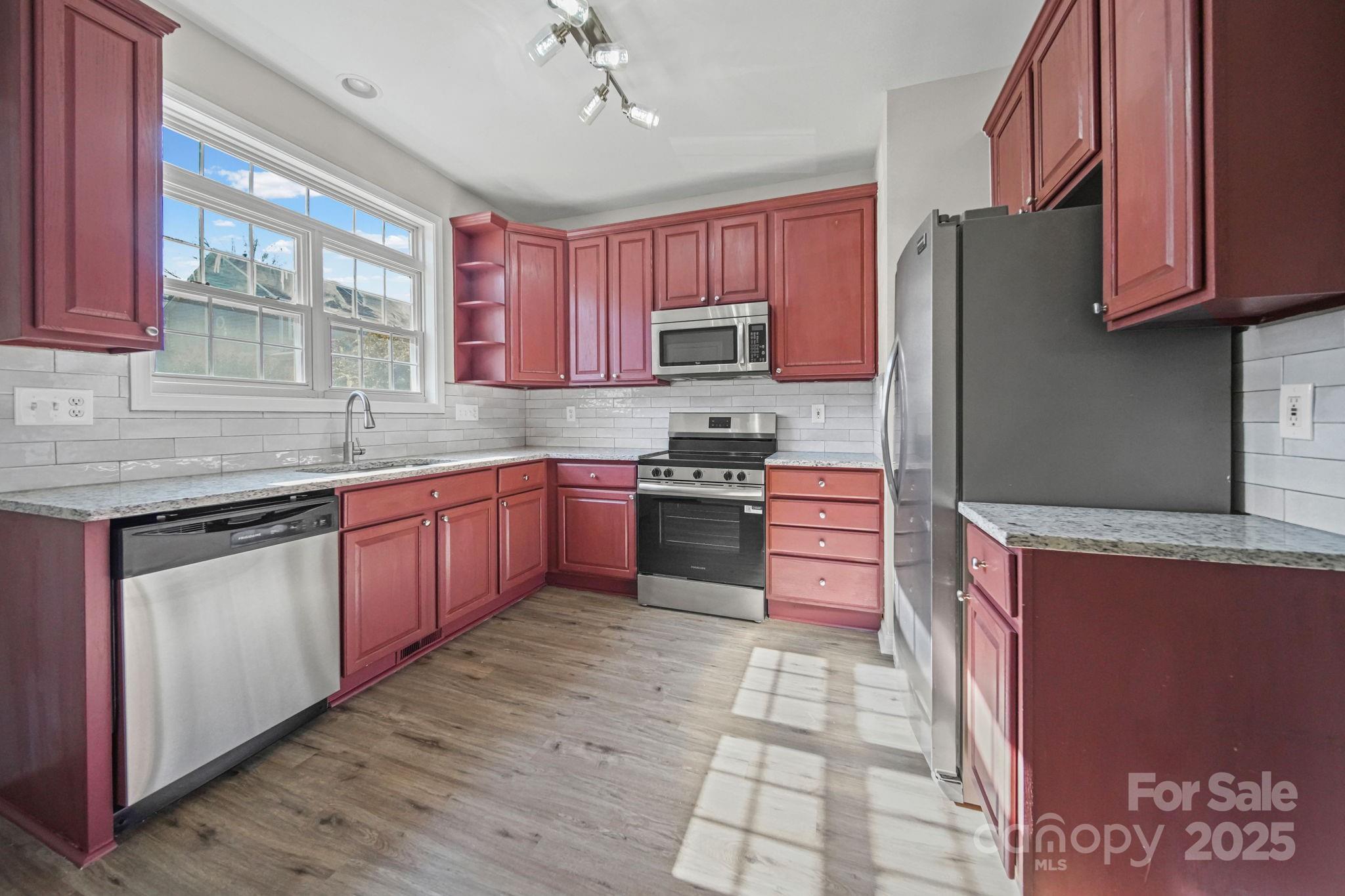a kitchen with stainless steel appliances granite countertop a sink counter space cabinets and a large window