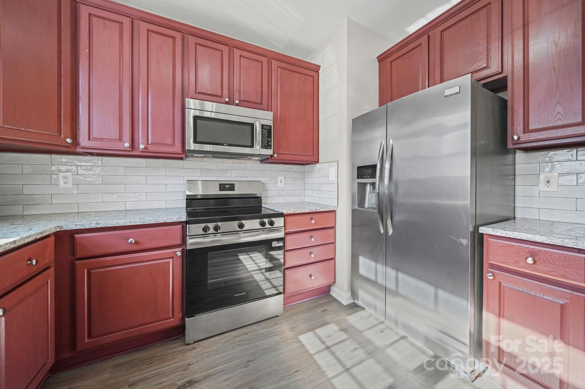 115 Sun Ridge Drive Mooresville, NC 28117 - Photo 6 of 30 a kitchen with stainless steel appliances granite countertop a refrigerator stove top oven and sink with wooden cabinets