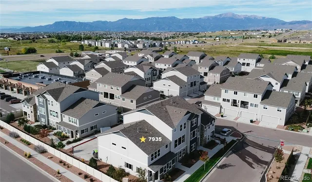 an aerial view of a city with lots of residential buildings and mountain view in back