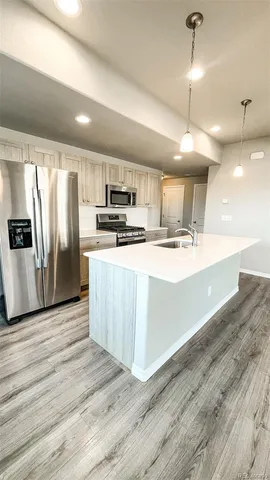 a large kitchen with stainless steel appliances kitchen island a large counter top and wooden floors
