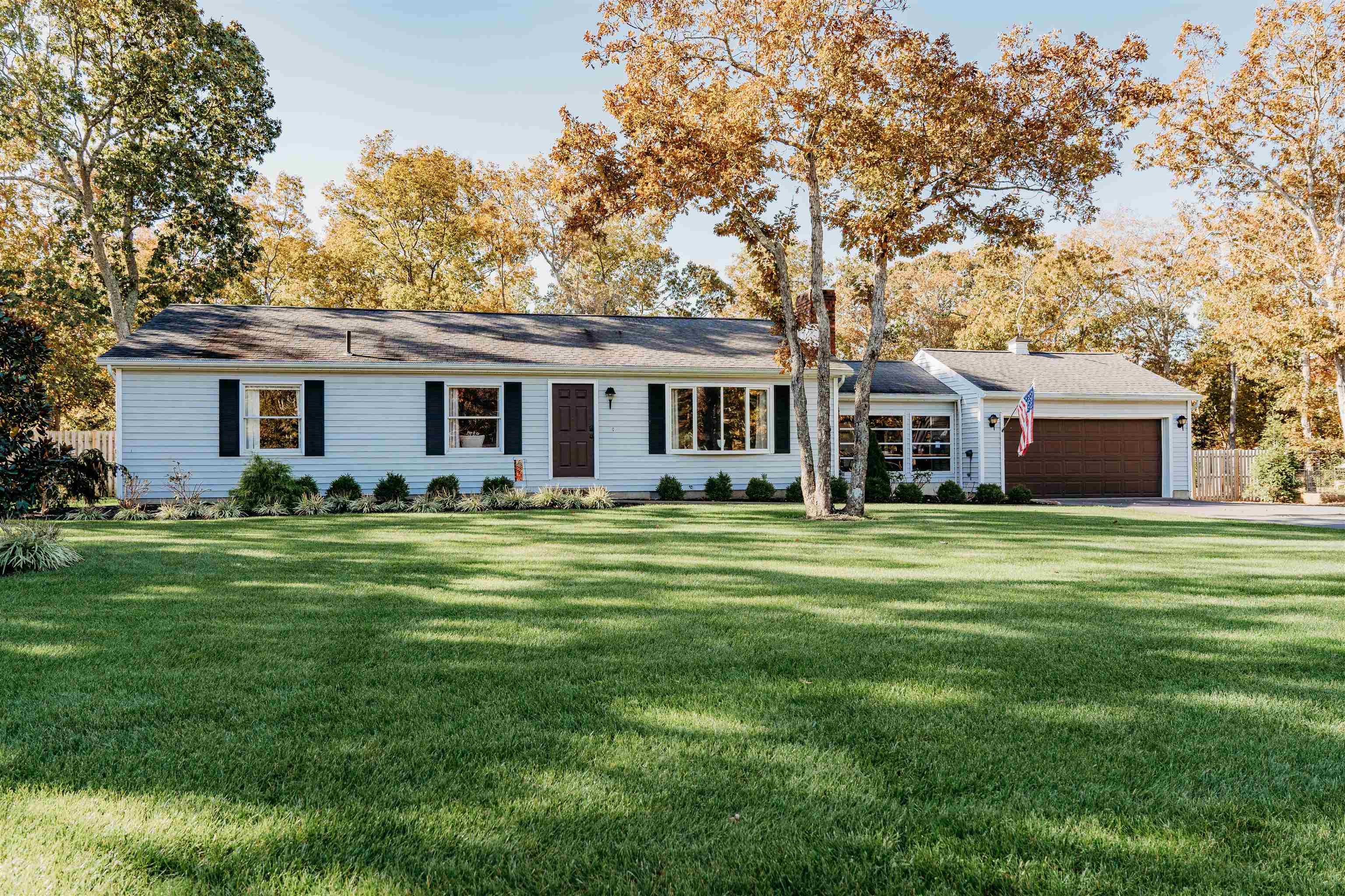 a front view of a house with a garden and trees