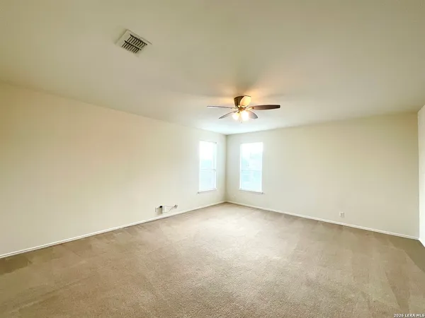 an empty room with a chandelier fan and windows