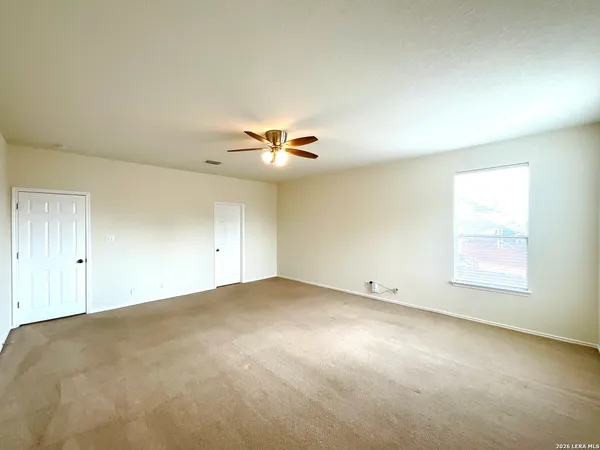 an empty room with windows and ceiling fan