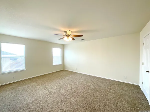 an empty room with windows and ceiling fan view