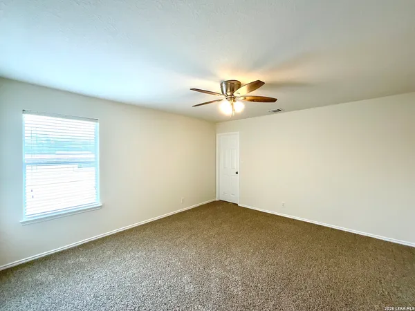 an empty room with a chandelier fan and window