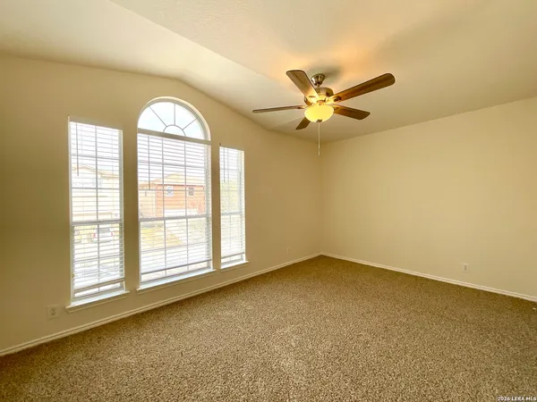 an empty room with windows and ceiling fan