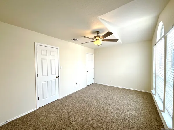 an empty room with a window and chandelier fan