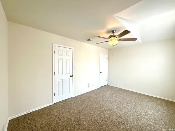 an empty room with a ceiling fan and wooden floor