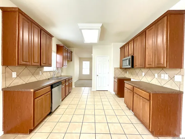 a large kitchen with stainless steel appliances wooden cabinets a stove top oven a sink and dishwasher