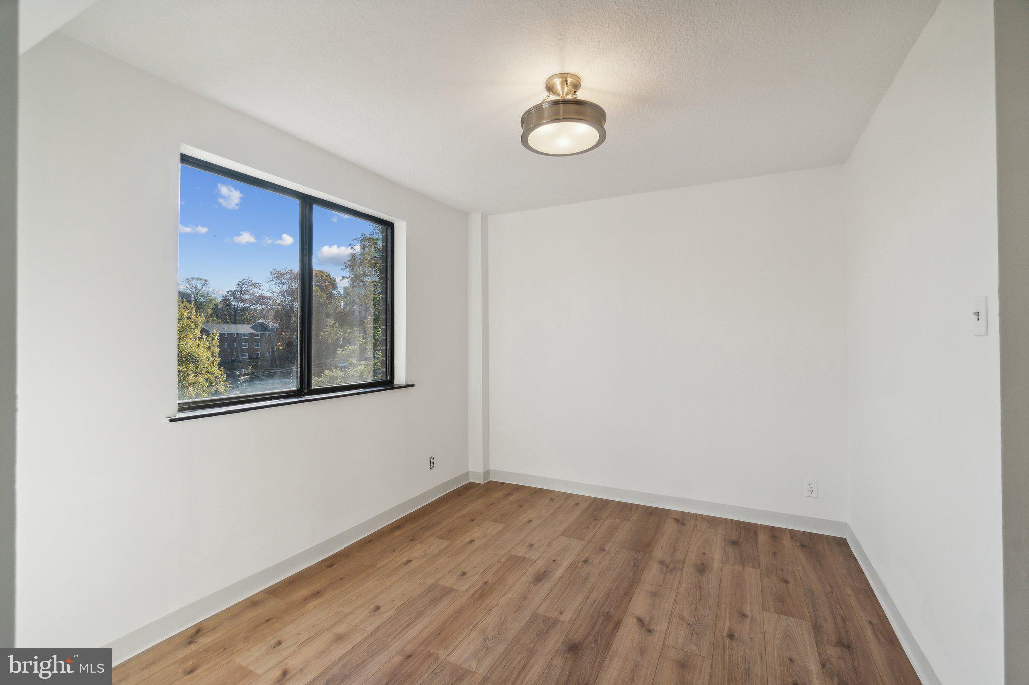 1401 North Rhodes Street, Unit 305 Arlington, VA 22209 - Photo 16 of 35 a view of an empty room with wooden floor and a window