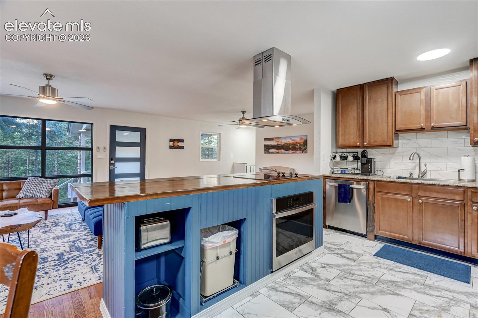 9955 Mesa Road Cascade, CO 80809 - Photo 20 of 41 Kitchen featuring a wood-finish island with a blue base, stainless steel appliances, and a tile backsplash