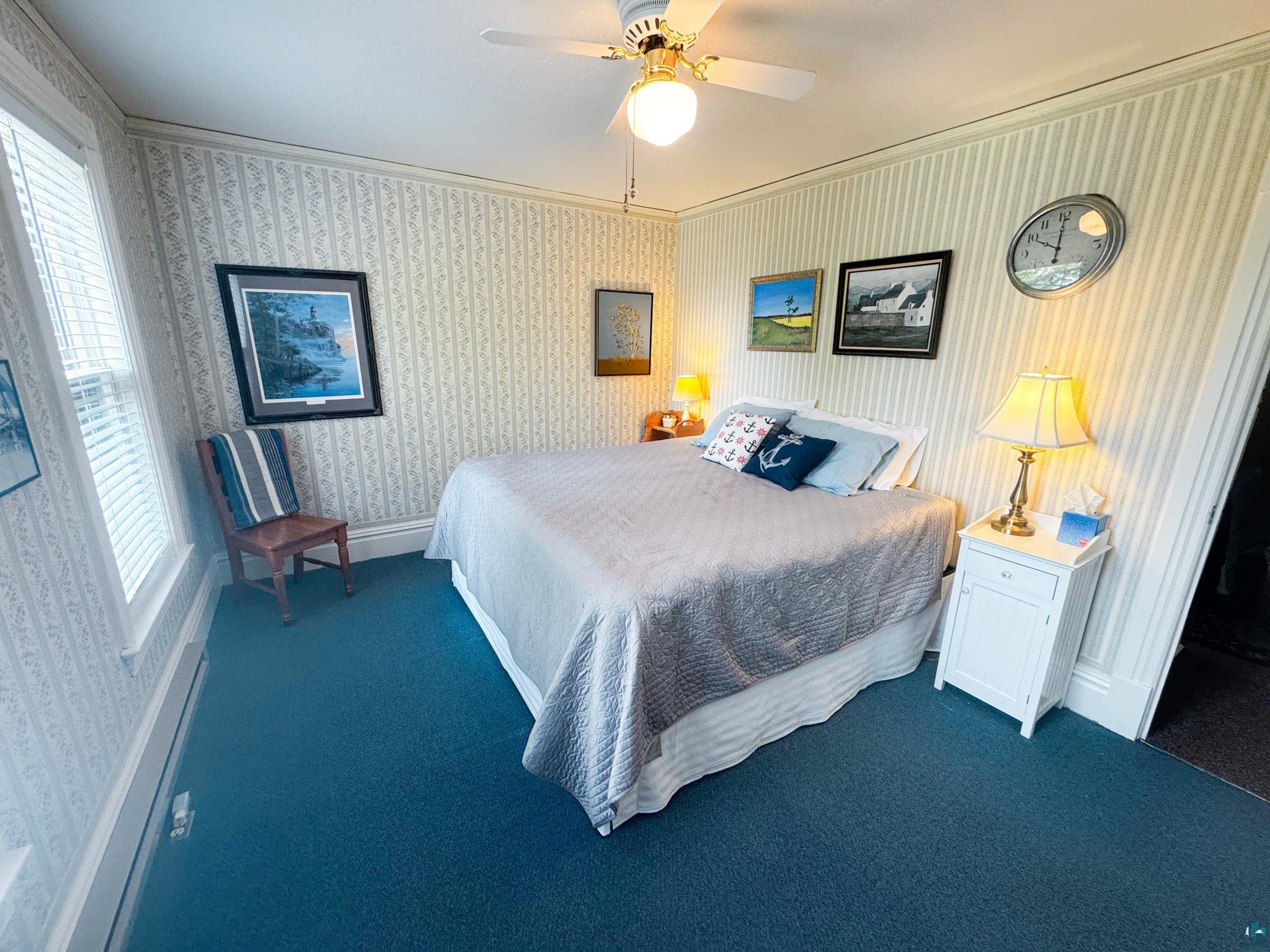 303 East 5th Street Washburn, WI 54891 - Photo 26 of 34 Textured wallpaper throughout, featuring a ceiling fan with integrated lighting, window with horizontal blinds, and blue carpet flooring