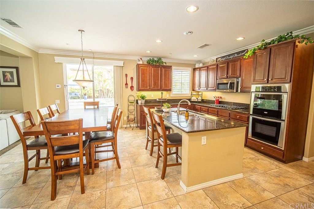 18622 Lurin Avenue Riverside, CA 92508 - Photo 8 of 33 a kitchen with stainless steel appliances granite countertop a stove top oven a sink a dining table and chairs