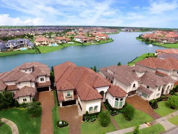 an aerial view of residential houses with outdoor space and lake view in back