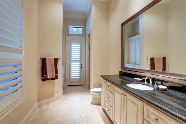 a bathroom with a granite countertop sink toilet and mirror