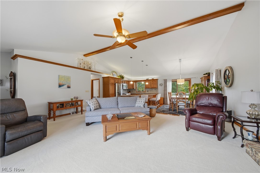 118 Manning Road Mogadore, OH 44260 - Photo 3 of 45 Expansive open-concept living area featuring vaulted ceilings, a ceiling fan with integrated lighting, wood-finish beams, and carpet flooring