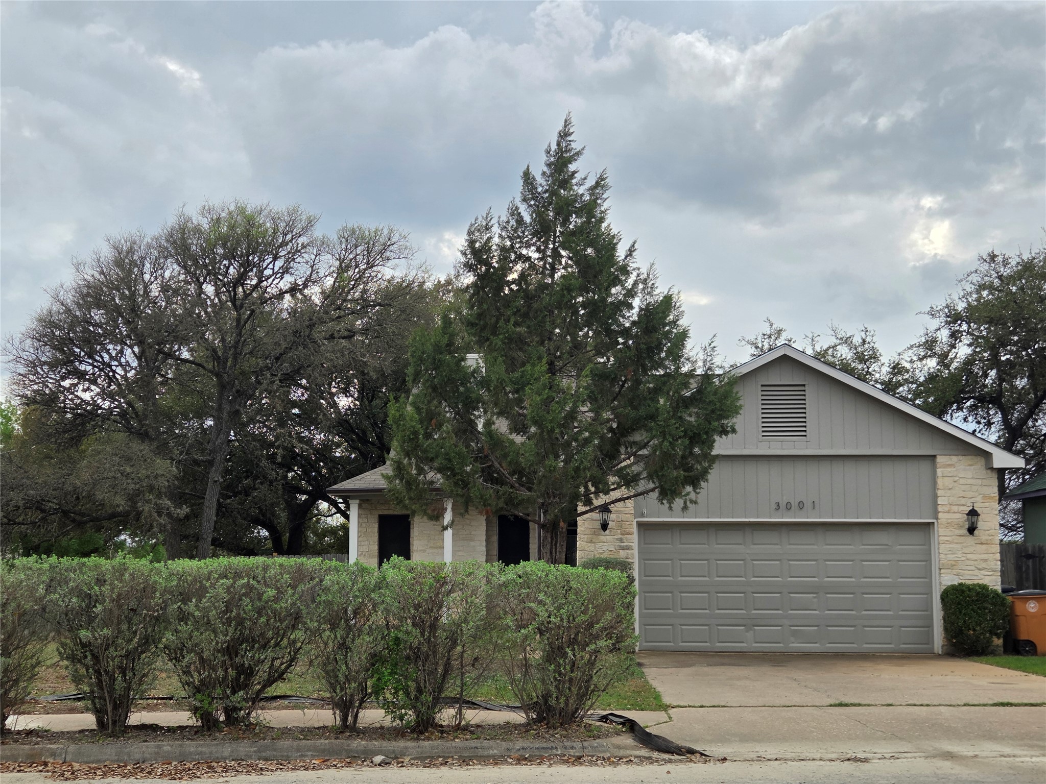 3001 Rochelle Drive Austin, TX 78748 - Photo 2 of 23 View of property hidden behind natural elements with an attached garage, driveway, and stone siding