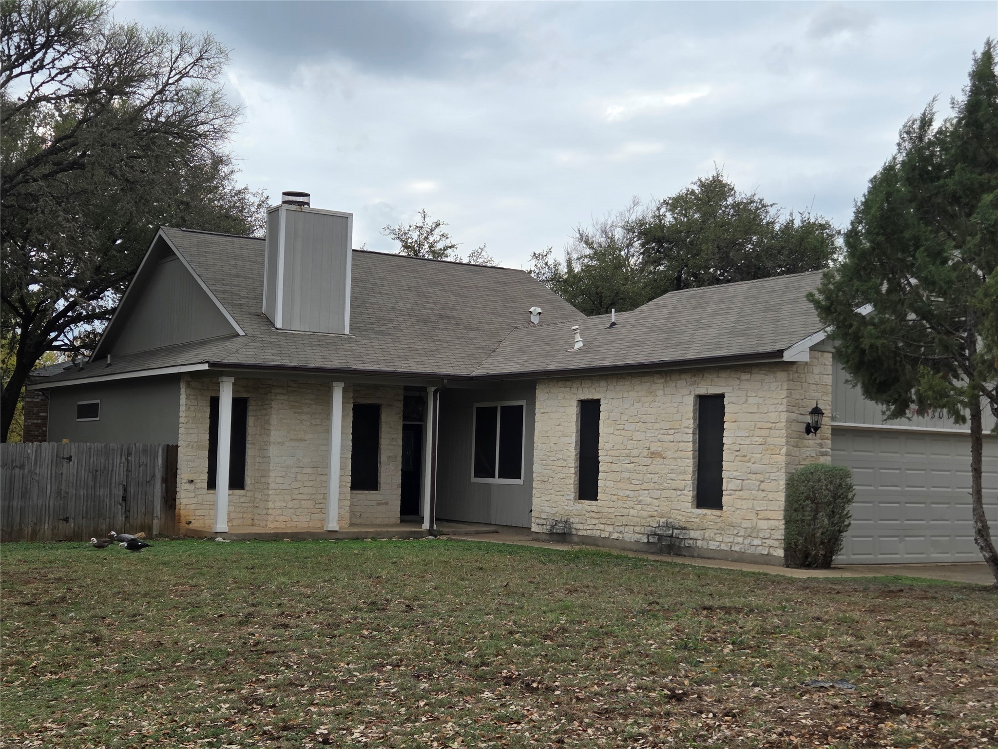 3001 Rochelle Drive Austin, TX 78748 - Photo 22 of 23 View of front of home with an attached garage, a chimney, stone siding, a patio area, and roof with shingles