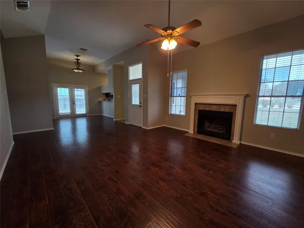 an empty room with wooden floor fireplace and windows