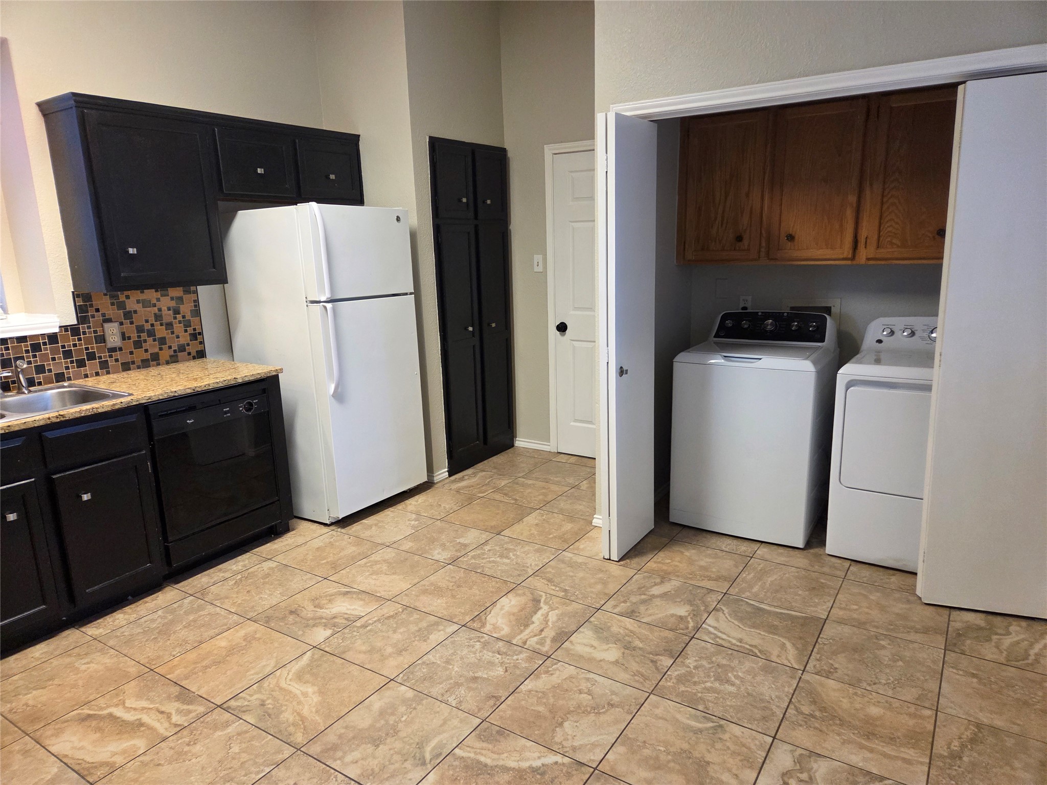 3001 Rochelle Drive Austin, TX 78748 - Photo 9 of 23 Kitchen with dishwasher, washer and clothes dryer, tasteful backsplash, dark cabinetry, and freestanding refrigerator