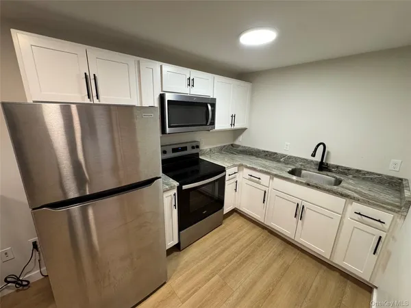 a kitchen with granite countertop white cabinets and white appliances