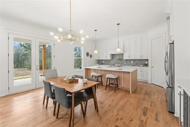 a kitchen with stainless steel appliances granite countertop a sink a stove a dining table and chairs with wooden floor