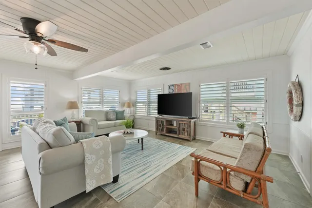 a living room with furniture a flat screen tv and a large window