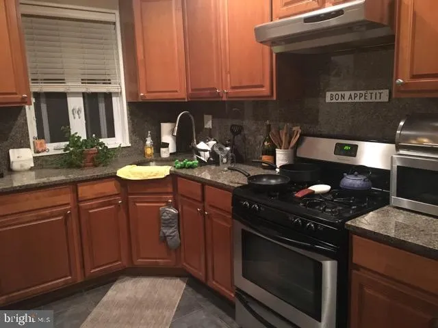 a kitchen with stainless steel appliances granite countertop a stove a sink and a microwave