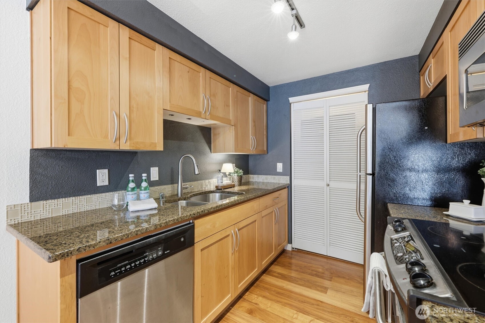 3045 20th Avenue West, Unit 303 Seattle, WA 98199 - Photo 11 of 28 a kitchen with stainless steel appliances granite countertop a sink stove and refrigerator