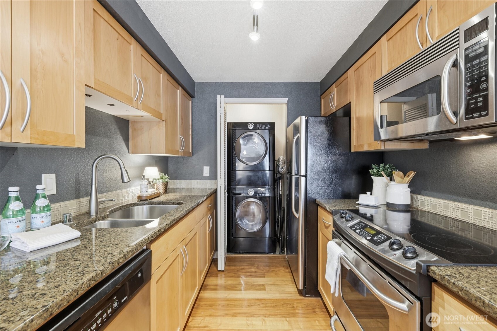3045 20th Avenue West, Unit 303 Seattle, WA 98199 - Photo 12 of 28 a kitchen with granite countertop a sink stove and cabinets