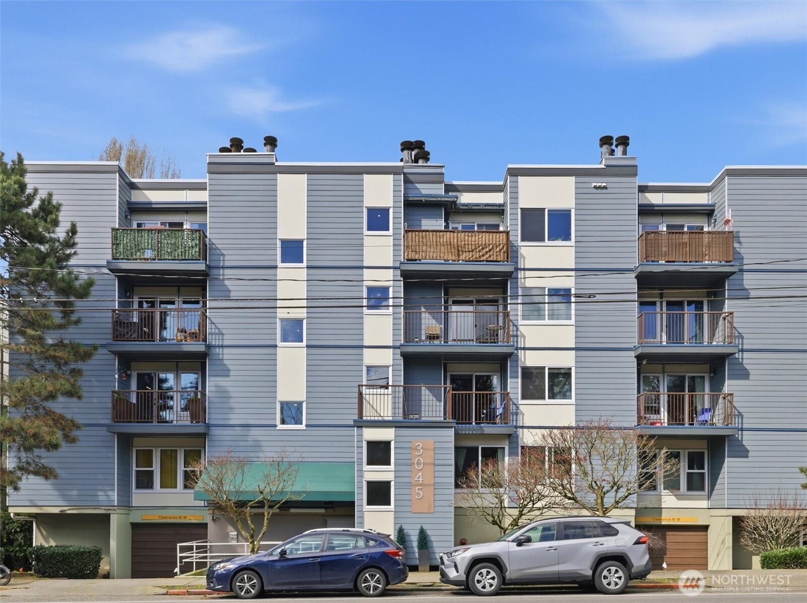 3045 20th Avenue West, Unit 303 Seattle, WA 98199 - Photo 2 of 28 a front view of a building with lot of cars and trees