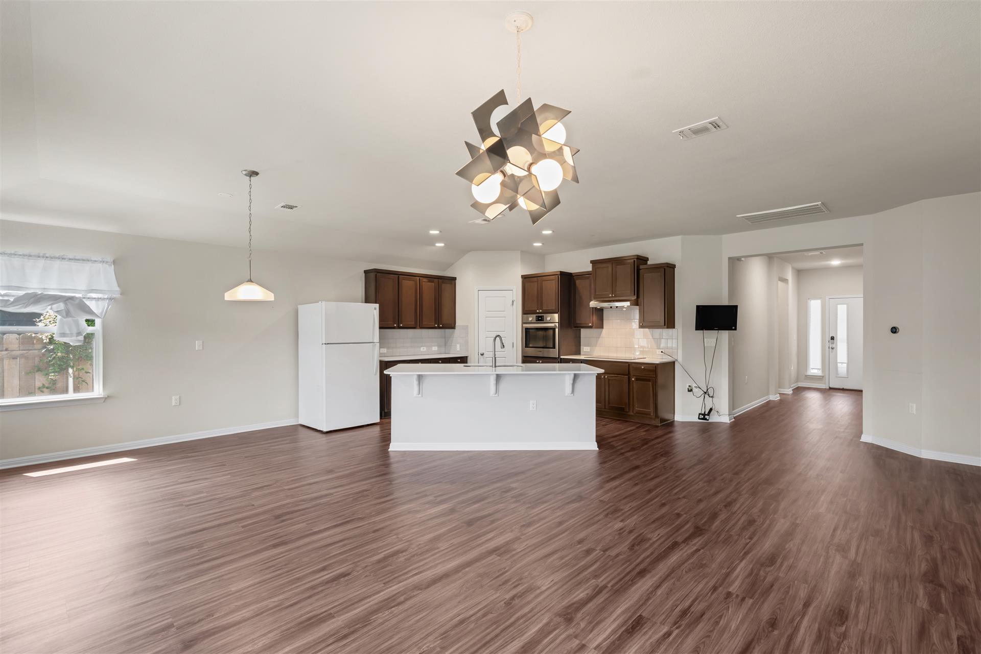 16512 Enamorado Road Manor, TX 78653 - Photo 24 of 31 A contemporary open-concept layout features rich wood flooring, an illuminated kitchen island, and inviting entrance.