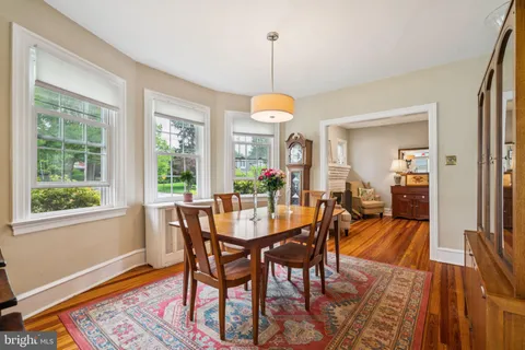 a dining room with wooden floor a chandelier a wooden table and chairs