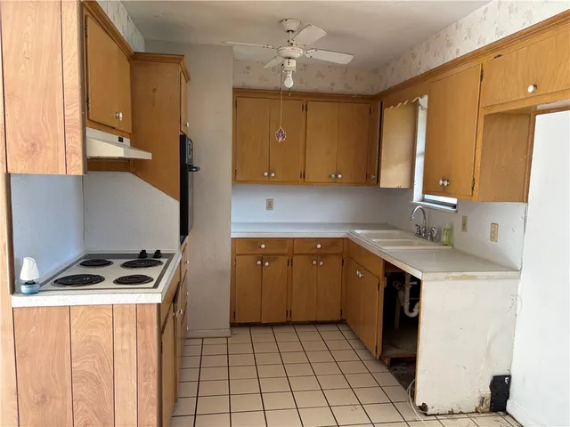 a kitchen with a sink a stove top oven and cabinets