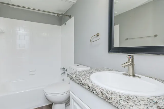 a bathroom with a granite countertop sink a toilet and a bathtub