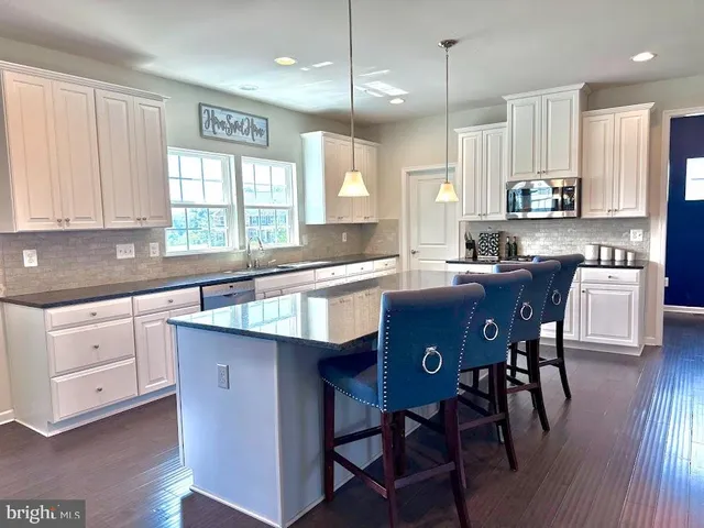 a kitchen with granite countertop a refrigerator sink and microwave