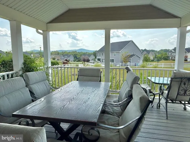 a view of a deck with couches chairs under an umbrella with wooden floor