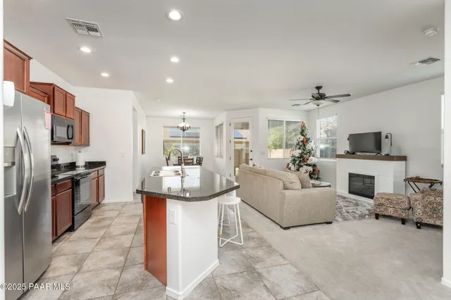 a living room with stainless steel appliances furniture a fireplace and a kitchen view